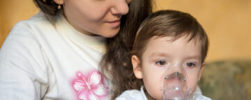 Photo of mother and child using a nebulizer. for story about whooping cough