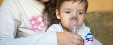 Woman with child using nebulizer. For a survey involving findings about whooping cough.
