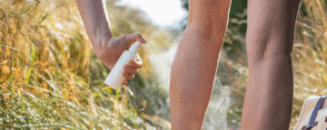 Image of a person applying bug spray.